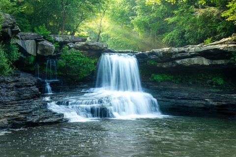 A backcountry waterfall in East Tennessee photographed as a long exposure, light filtering through the trees above.